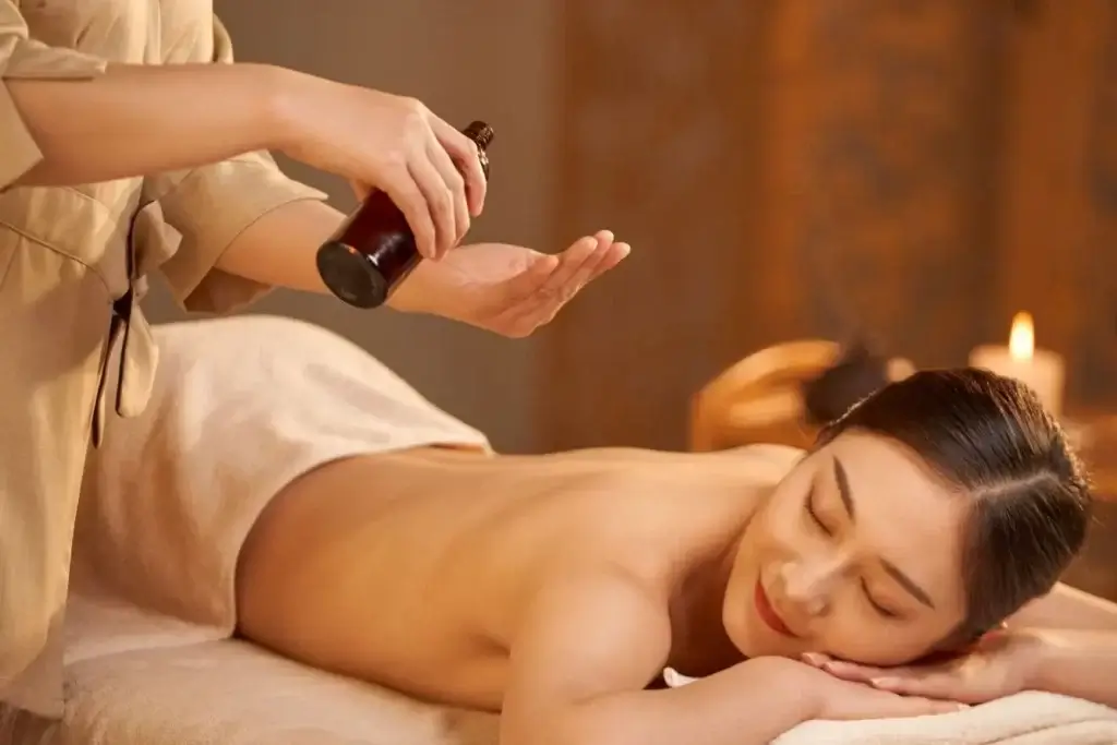 Người đang được massage thư giãn với dầu, nằm trên bàn massage trong không gian ấm cúng với ánh nến.