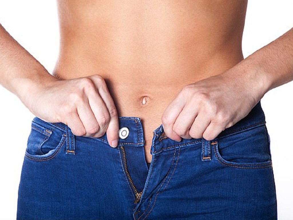 Người đang kéo khóa quần jeans xanh, tập trung vào phần eo và quần.