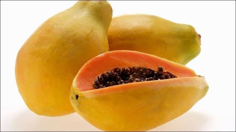 Ba quả đu đủ chín, một quả được cắt đôi, lộ phần thịt màu cam và hạt màu đen bên trong.