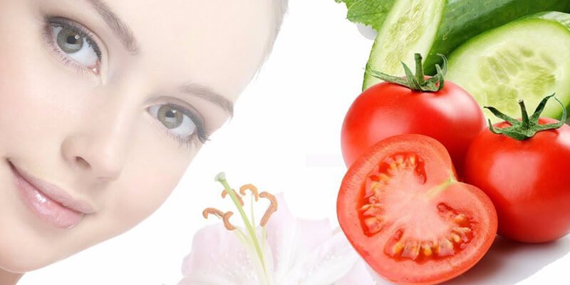 Khuôn mặt người cận cảnh bên cạnh dưa leo, cà chua và hoa trắng.