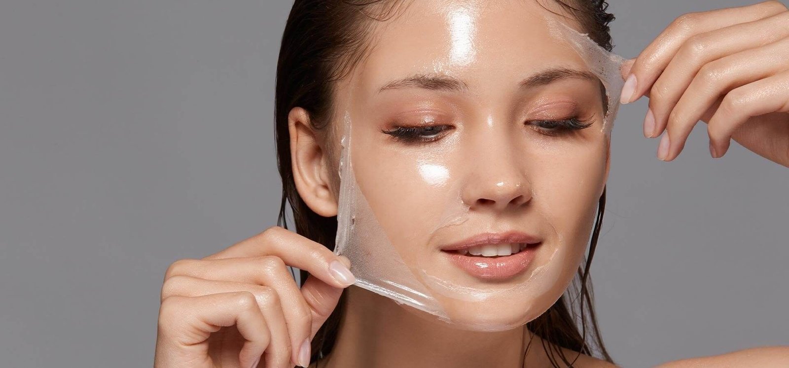 Người đang gỡ mặt nạ dưỡng da trong suốt khỏi mặt, với làn da sáng bóng.