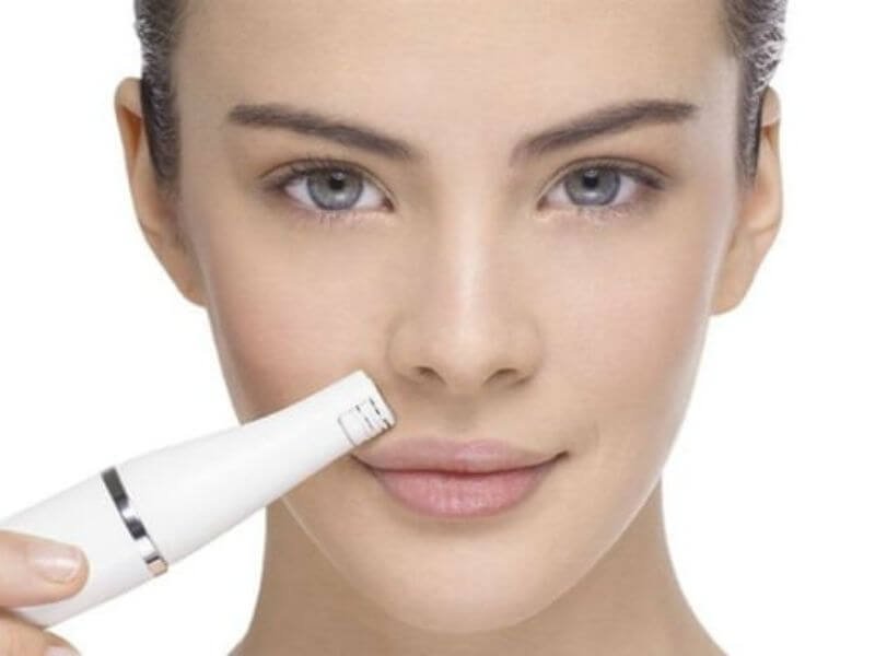 Người đang sử dụng thiết bị làm đẹp da mặt, tập trung vào vùng mũi.