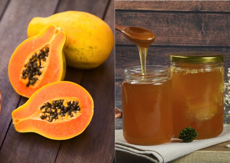 Đu đủ chín cắt đôi bên trái và hai hũ mật ong bên phải trên nền gỗ.