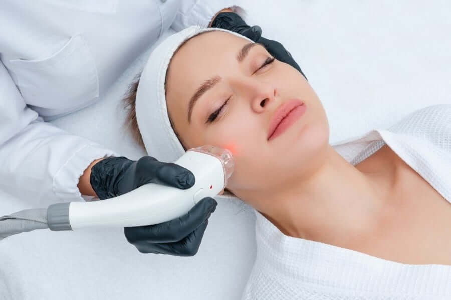 Người đang nằm thư giãn, được chăm sóc da mặt bằng thiết bị công nghệ cao trong môi trường spa.