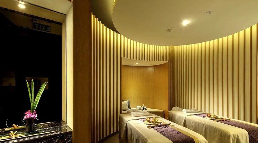 Phòng spa ánh sáng dịu, có hai giường massage và hoa tươi trang trí tạo cảm giác thư giãn.