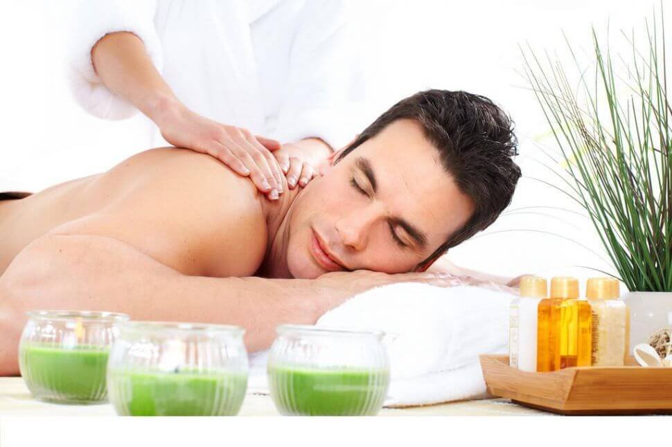Người đang được massage thư giãn, xung quanh có nến xanh và chai lọ, tạo cảm giác spa thoải mái.