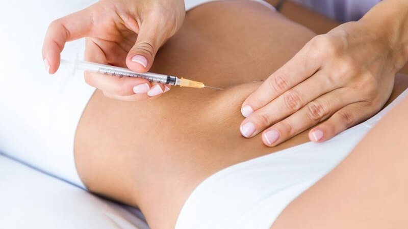 Người chuẩn bị tiêm vào vùng bụng trong bối cảnh y tế.